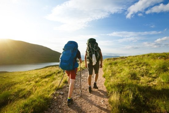 Deux marcheurs de l’arrière sur un chemin avec rivière et montagne à gauche