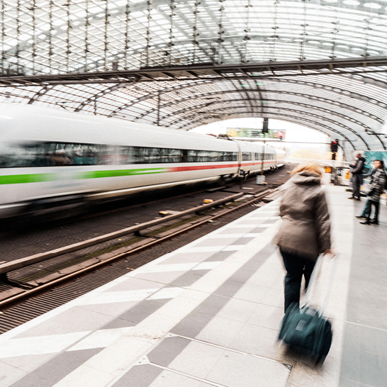  Une femme marche sur un quai de train à Berlin, tirant une valise derrière elle.