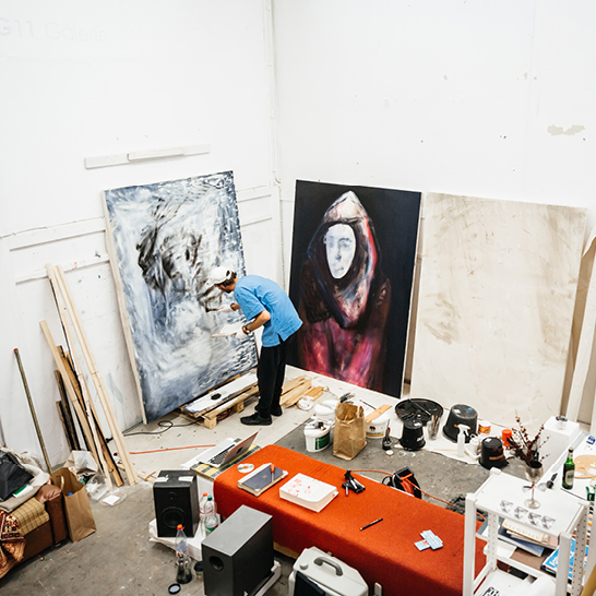 Un homme peint une toile dans un studio à Berlin.