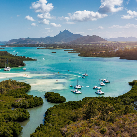 Mehrere Boote liegen im Wasser, umgeben von der schönen Landschaft von Mauritius.